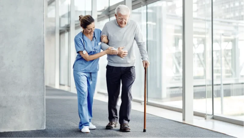 Nurse helping an elderly person to walk inside the hospital